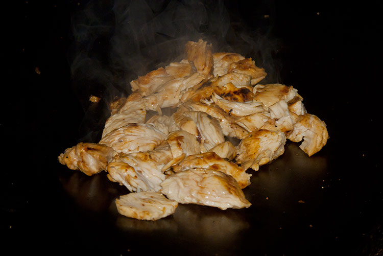 After it's been flame-broiled, this chicken breast is sliced on the flat-top.